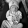 baby, newborn, sleeping, hat, pom_poms, onesie, hands, face, person, lap, black_and_white, cozy, cute, indoor, bottle, resting, soft, infant, clothing, peaceful