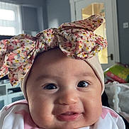 Willow is registered to the contest to win money with this photo: baby, infant, headband, bow, smile, face, clothing, pink, white, star_pattern, indoor, person, cute, cheeks, eyes, portrait, child, happy, apparel, babywear