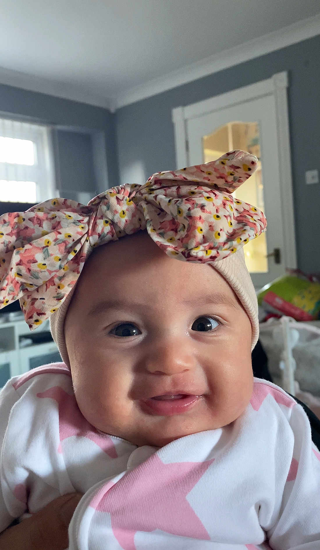 Willow is registered to the contest to win money with this photo: baby, infant, headband, bow, smile, face, clothing, pink, white, star_pattern, indoor, person, cute, cheeks, eyes, portrait, child, happy, apparel, babywear