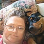 Cheyenne joined the competition — help win amazing prizes! woman, dog, glasses, pillow, floral_pattern, indoor, floor, chair, wooden_floor, pet, relaxed, lying_down, casual_clothing, face, companion, closeup, resting, home, comfort, animal