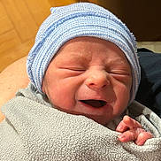 Luke joined the competition — help win amazing prizes! newborn, baby, infant, swaddled, striped_hat, beanie, blanket, closeup, face, cheeks, nose, mouth, hand, fingers, skin, indoor, wood_floor, portrait, cute, expression