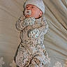 Braxton is registered to the contest to win money with this photo: baby, bed, bedspread, calm, child, cozy, dinosaur_print, floral_pattern, indoors, infant, knit_hat, lying_down, mittens, newborn, onesie, pacifier, photography, portrait, sleeping, stuffed_toy