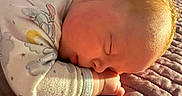 Braxton is registered to the contest to win money with this photo: baby, blanket, clothing, cozy, curled_up, ear, face, hair, hands, indoors, infant, onesie, peaceful, portrait, quilt, resting, sleeping, star_pattern, sunlight, warm_lighting