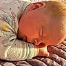 Braxton is registered to the contest to win money with this photo: baby, sleeping, infant, portrait, peaceful, indoors, blanket, quilt, onesie, clothing, star_pattern, sunlight, warm_lighting, curled_up, resting, face, ear, hair, hands, cozy
