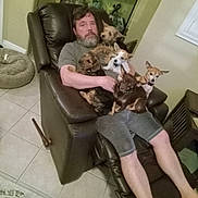 Peter Harbauer is registered to the contest to win money with this photo: aquarium, beard, brown_dog, casual, companion, dog, furniture, home, indoor, living_room, man, multiple_dogs, pet_bed, recliner, relaxing, seated, shorts, small_dog, tile_floor, white_dog
