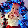 baby, infant, child, red_clothing, white_shirt, headband, holiday_lights, decorations, blue_lights, red_stars, festive, cute, portrait, indoors, hands, face, expression, background, celebration, warm