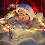 baby, blanket, candy_cane, child, christmas, cute, decorations, fairy_lights, festive, holiday, indoors, infant, plush, portrait, red, santa_hat, smiling, soft_texture, teddy_bear, white