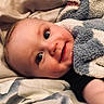 Declan joined the competition — help win amazing prizes! baby, infant, child, face, portrait, smiling, eyes, blanket, swaddled, bed, bedding, indoors, close_up, lying_down, cozy, blue, white, soft_lighting, candid, cute