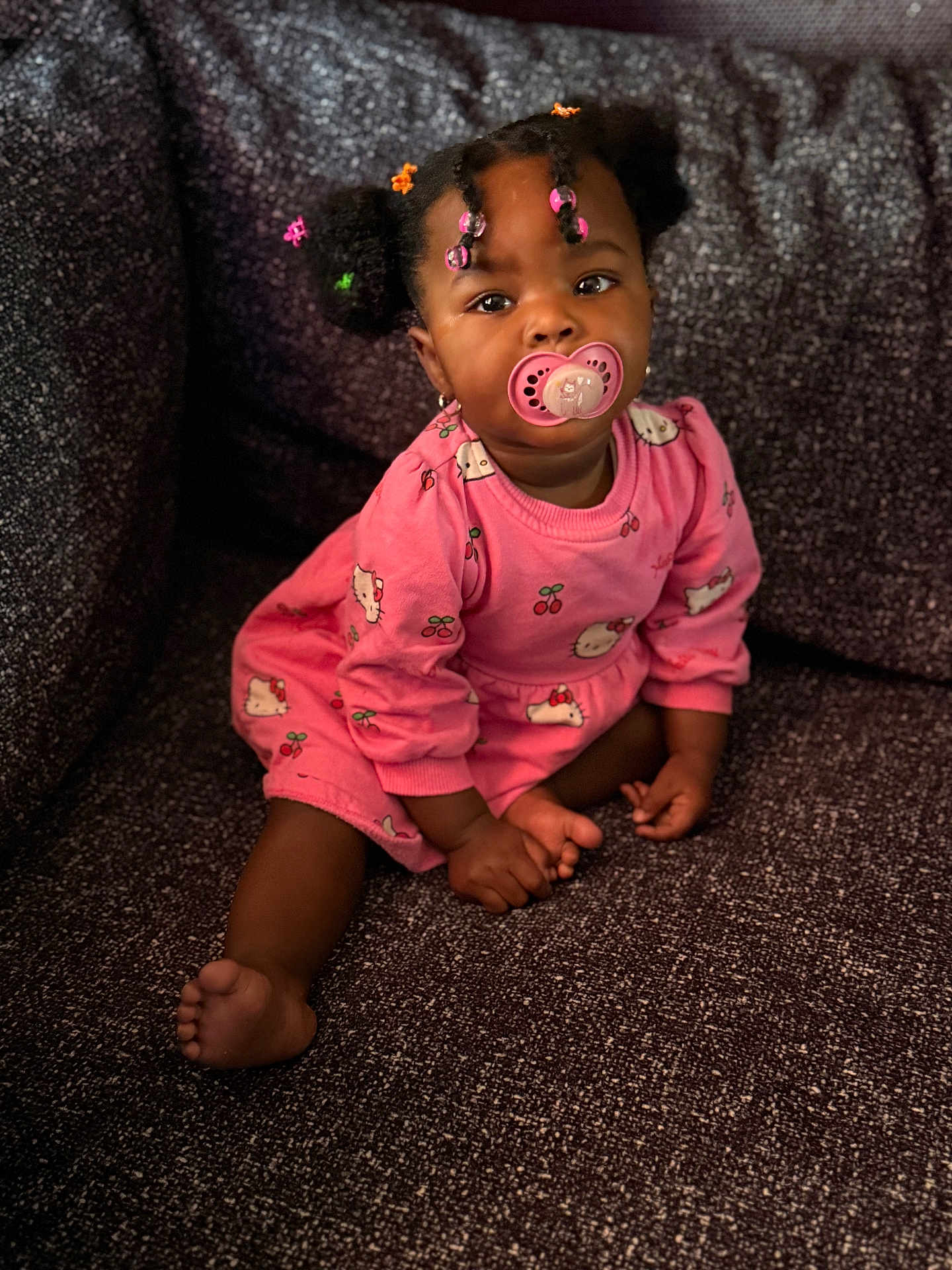 Kennayah a rejoint le concours — aidez-le/la à gagner de superbes lots ! baby, child, girl, pacifier, pink_dress, hair_beads, sitting, couch, indoors, cute, portrait, smiling, infant, young_child, clothing, foot, hand, skin, furniture, comfort