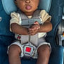 baby, child, car_seat, safety_harness, socks, clothing, face, hands, legs, seat, warning_label, infant, cute, wide_eyes, tongue_out, person, indoor, seatbelt, baby_clothes, closeup