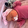 baby, newborn, pacifier, headband, pink_clothing, pink_blanket, sleeping, plush_toy, zebra_pattern, infant, cute, soft_texture, peaceful, child, resting, indoors, portrait, small_hands, cozy, adorable