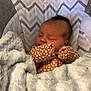Amari is registered to the contest to win money with this photo: baby, newborn, sleeping, blanket, onesie, patterned_clothing, cozy, cushion, seat, zigzag_pattern, soft_texture, infant, face, peaceful, resting, indoor, cute, child, warm, comfort