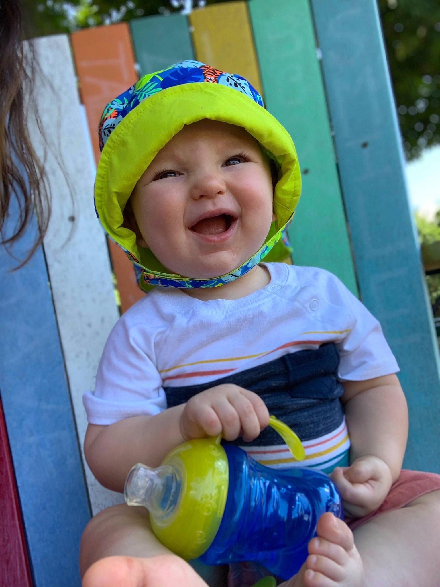Theo is registered to the contest to win money with this photo: baby, baby_products, baby_toddler_clothing, cap, child, event, fashion_accessory, fun, green, happy, headwear, leisure, person, personal_protective_equipment, play, recreation, skin, smile, sun_hat, thumb
