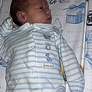 George is registered to the contest to win money with this photo: newborn, baby, onesie, striped_clothing, infant, sleeping, lying_down, baby_changing_mat, blue, white, pattern, cute, face, head, small_person, child, soft_lighting, indoor, resting, cozy