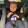 toddler, child, car_seat, snack, smile, happy, car_interior, seatbelt, clothing, hands, face, blue_eyes, hair, window, vehicle, safety, daylight, candid, cute, joyful