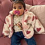 baby, child, pacifier, pigtails, jacket, heart_pattern, couch, pink, plush, clothing, denim, shoes, indoors, cute, sitting, person, face, expression, cozy, toy