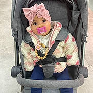 Açelya a rejoint le concours — aidez-le/la à gagner de superbes lots ! baby, stroller, pacifier, headband, pink_bow, jacket, fluffy_jacket, leopard_print_shoes, child, infant, seated, clothing, cute, indoor, floor_tiles, safety_harness, accessory, face, portrait, expression