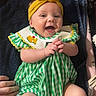 Stevie is registered to the contest to win money with this photo: baby, smiling, headband, yellow, green, checkered, clothing, infant, happy, hands, towel, fabric, cute, person, skin, face, lying, indoors, child, portrait