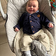 Conor a rejoint le concours — aidez-le/la à gagner de superbes lots ! baby, smiling, infant, cardigan, pants, socks, baby_seat, cushion, toy, floor, tile, footwear, indoor, child, happy, person, cute, comfort, clothing, seat