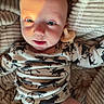baby, infant, pacifier, blanket, clothing, diaper, face, person, lying_down, cute, moose_pattern, soft, cozy, child, expression, skin, warm_light, indoors, comfort, newborn