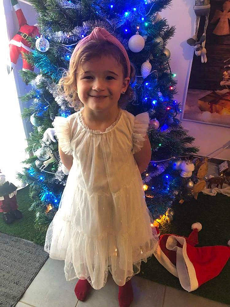 Emy participe au concours pour gagner de l'argent avec cette photo : baby_toddler_clothing, blue, christmas_decoration, christmas_ornament, christmas_tree, dress, electric_blue, event, fun, happy, holiday_ornament, joy, light, ornament, person, plant, purple, smile, standing, toddler
