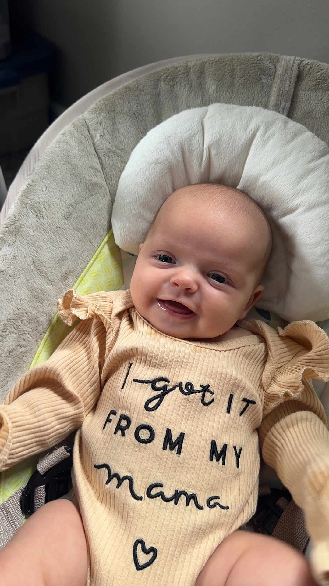 Kenidy joined the competition — help win amazing prizes! baby, smiling, infant, clothing, text_on_clothing, cushion, seat, indoors, portrait, cute, child, person, soft_texture, beige, happy, young_child, closeup, head, face, apparel