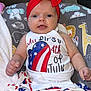 baby, infant, red_bow, headband, 4th_of_july, patriotic_clothing, dress, sitting, cushion, elephant, giraffe, lion, happy_baby, indoor, smiling, cute, child, face, white_clothing, american_flag_pattern