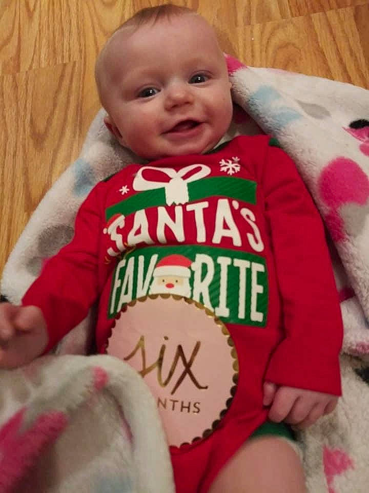 Aliza is registered to the contest to win money with this photo: baby, baby_toddler_clothing, cheek, comfort, eye, face, facial_expression, finger, happy, head, jersey, mammal, organ, person, product, skin, sleeve, smile, t_shirt, thigh