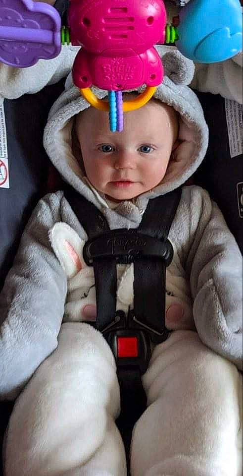 Aliza joined the competition — help win amazing prizes! baby, baby_carriage, baby_toddler_clothing, cap, cheek, comfort, costume_hat, eye, eyebrow, headwear, helmet, human_body, jacket, knit_cap, person, pink, seat_belt, skin, sleeve, textile