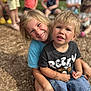 child, children, smiling, outdoor, playground, hug, happy, blond_hair, casual_clothing, shorts, tshirt, wood_chips, group, friends, summer, daylight, park, cute, sitting, people