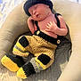 newborn, baby, sleeping, knitted_clothing, hat, pants, yellow, black, beige, cushion, blanket, cozy, infant, resting, cute, indoors, soft, portrait, child, peaceful