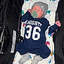 Rowan is registered to the contest to win money with this photo: newborn, baby, sleeping, pacifier, onesie, beanie, blanket, stroller, infant, clothing, striped_socks, face, hand, footwear, child, rest, comfort, indoor, portrait, cute