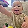 Kaleo is registered to the contest to win money with this photo: baby, infant, smiling, laughing, toy, plush_toy, cow_toy, onesie, striped_clothing, couch, sofa, window_blinds, curtain, hand, arm, face, eyes, mouth, happy, toddler