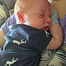 Riley is registered to the contest to win money with this photo: baby, newborn, sleeping, infant, onesie, deer_print, person, couch, indoor, closeup, face, ear, arm, skin, holding, comfort, rest, cute, tender, soft_light