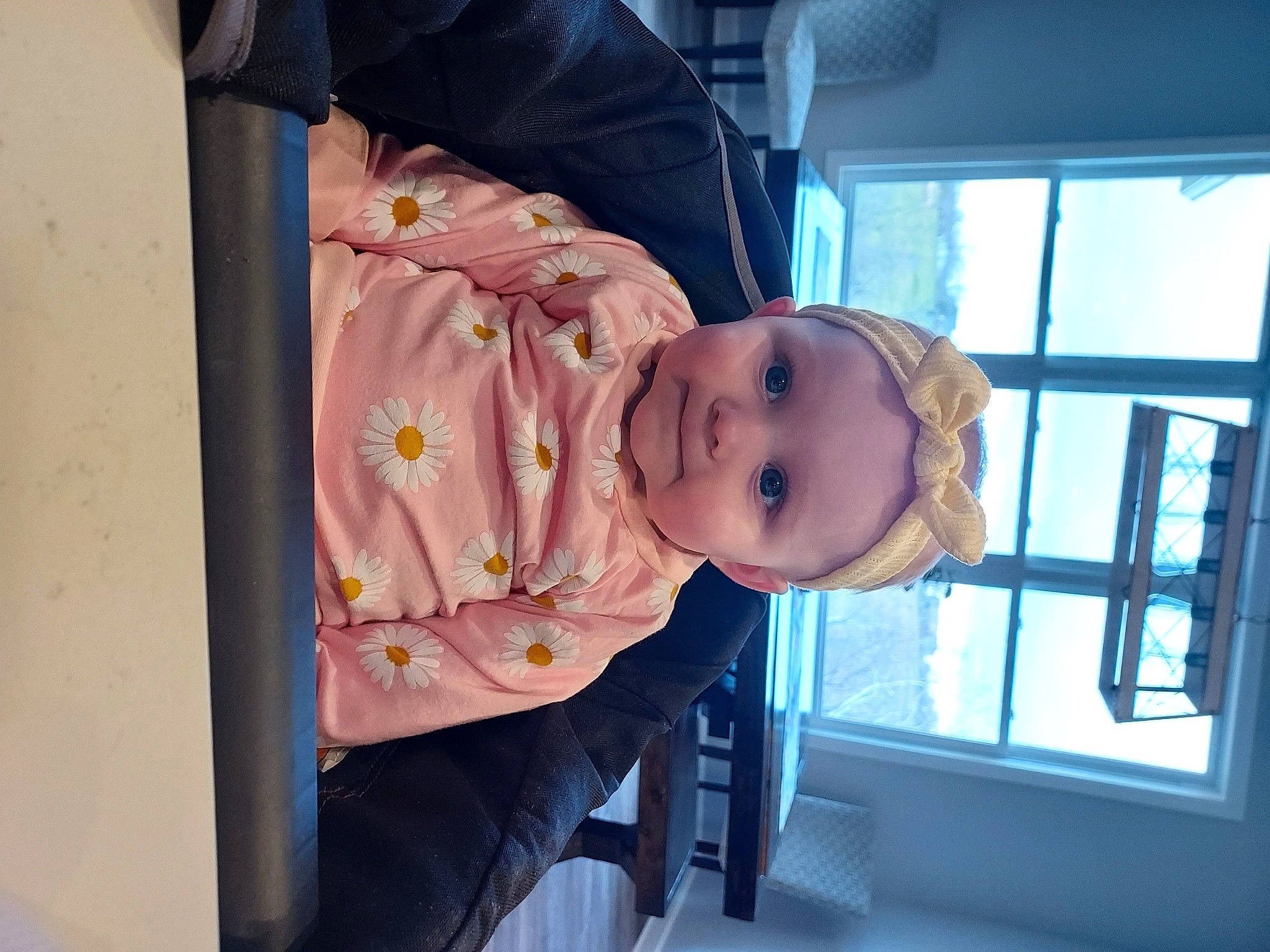 Vera is registered to the contest to win money with this photo: baby, baby_products, baby_safety, baby_toddler_clothing, cheek, child, comfort, dress, happy, hat, headwear, magenta, person, room, sitting, sleeve, smile, toddler, tree, window