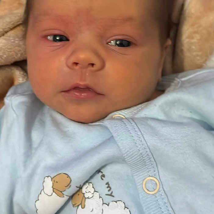 Lachlan is registered to the contest to win money with this photo: baby, blanket, blue_outfit, child, closeup, clothing, cozy, cute, expression, face, indoors, infant, lying_down, newborn, peaceful, portrait, sheep_print, sleepwear, soft_texture, warm_colors