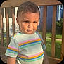 Koda is registered to the contest to win money with this photo: child, toddler, boy, outdoor, sunlight, striped_shirt, wooden_deck, railing, grass, portrait, smirk, short_hair, casual_clothing, daylight, person, nature, summer, expression, standing, curious