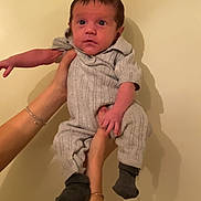 Isaiah joined the competition — help win amazing prizes! baby, infant, hands, gray_outfit, socks, person, portrait, indoor, wall, curious, small, child, cute, holding, human, skin, face, expression, young, looking