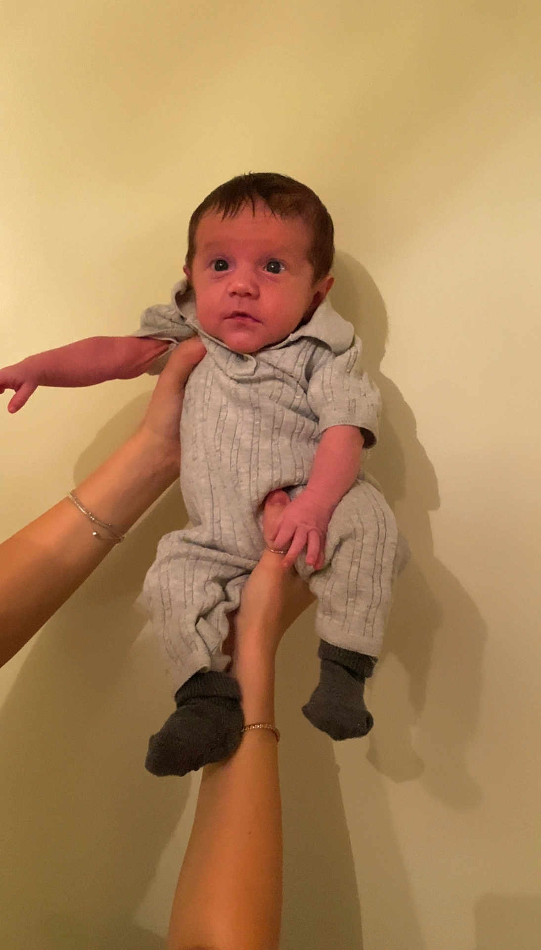Isaiah joined the competition — help win amazing prizes! baby, infant, hands, gray_outfit, socks, person, portrait, indoor, wall, curious, small, child, cute, holding, human, skin, face, expression, young, looking