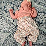 baby, sleeping, infant, headband, flower, patterned_blanket, peach_top, floral_pants, bare_feet, cute, peaceful, portrait, child, soft_lighting, indoor, resting, adorable, small_hands, cozy, relaxed