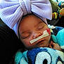 baby, sleeping, bow, headband, nasal_tube, blanket, colorful, cartoon, person, hand, closeup, resting, infant, cute, soft, cozy, child, face, toddler, peaceful