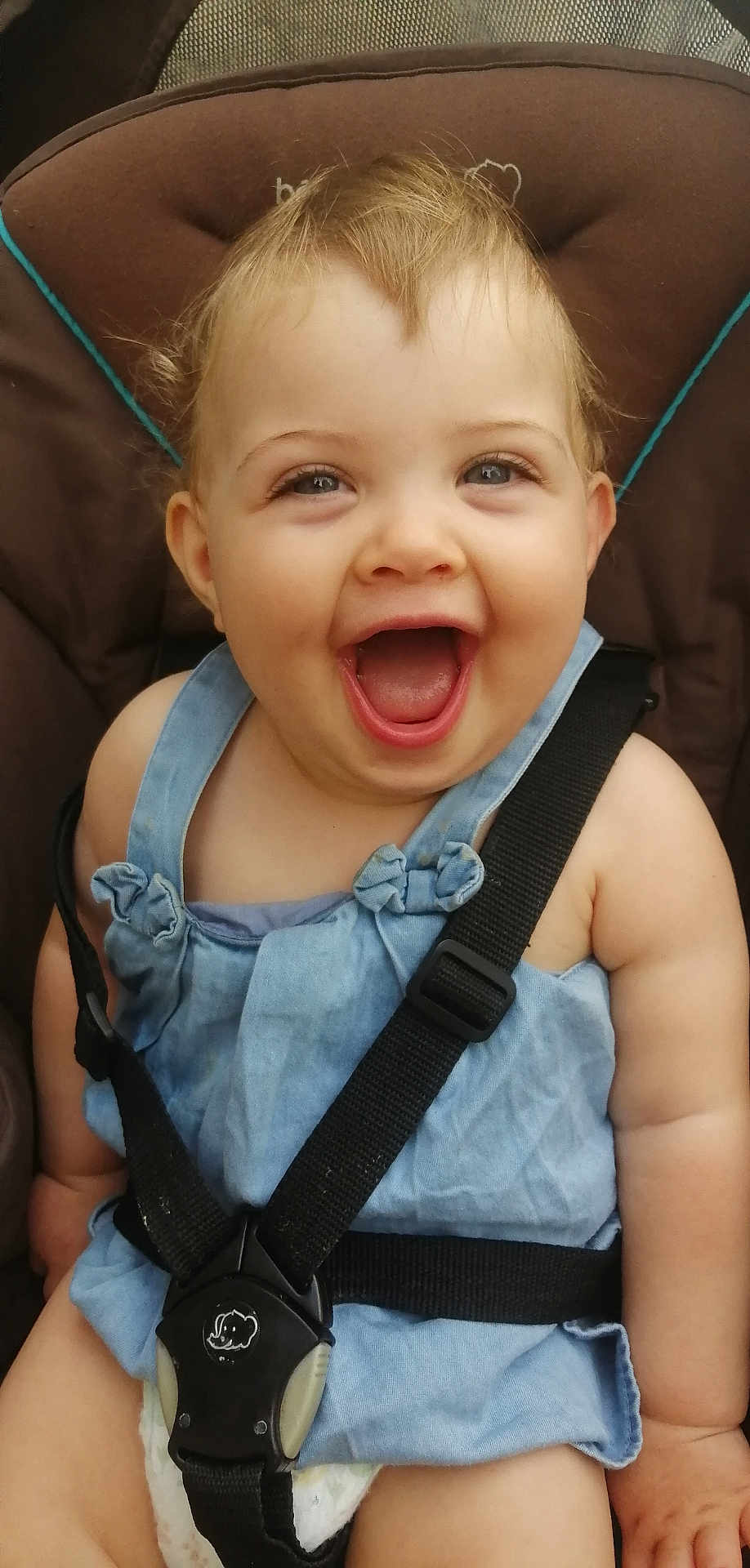 Ana participe au concours pour gagner de l'argent avec cette photo : baby, child, smiling, happy, car_seat, seatbelt, blue_dress, infant, cute, face, skin, cheerful, sitting, straps, young, person, indoors, human, expression, little
