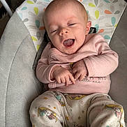 Penelope is registered to the contest to win money with this photo: baby, infant, smile, yawn, pajamas, pink_sweater, baby_chair, cushion, patterned_fabric, hands, face, headrest, indoor, cozy, cute, child, person, relaxing, comfort, happy