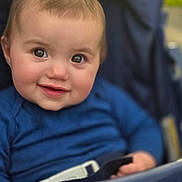 Willow is registered to the contest to win money with this photo: baby, child, smile, face, blue_clothing, stroller, seatbelt, cute, portrait, infant, happy, young_child, person, closeup, human, outdoor, daylight, expression, skin, head