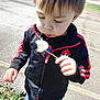 Colson is registered to the contest to win money with this photo: child, toddler, dandelion, outdoor, plant, flower, blowing, black_jacket, red_stripes, adidas, casual_clothing, curly_hair, sunlight, nature, pavement, greenery, young_child, person, cute, spring