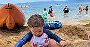 Nicholas is registered to the contest to win money with this photo: child, toddler, sand, beach, bucket, water, lake, sky, clouds, swimwear, sandcastle, toy, people, kayak, sitting, playing, summer, outdoor, vacation, nature