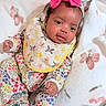 baby, infant, child, onesie, bib, headband, bow, blanket, butterfly, floral_pattern, sleepwear, cute, face, skin, hand, footwear, soft_texture, lying_down, indoor, portrait