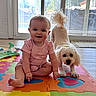 Scarlet is registered to the contest to win money with this photo: baby, child, dog, indoor, play_mat, pink_clothing, smiling, sitting, pet, white_dog, window, glass_door, floor, wood_floor, toy, colorful, home, cute, happy, young_child