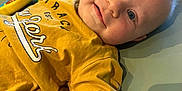 Elio participe au concours pour gagner de l'argent avec cette photo : baby, infant, smiling, yellow_shirt, toy, indoor, child, cute, playful, lying_down, pacifier, face, closeup, happy, young_child, casual_clothing, soft_surface, blue_eyes, light_hair, baby_toys