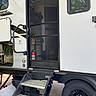 Merlin is registered to the contest to win money with this photo: dog, cat, trailer, rv, camper, screen_door, steps, wheel, tire, vehicle, outdoor, camping, travel, pets, animal, doorway, window, fire_extinguisher, sunlight, road